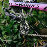 Close-up of a bicycle chain and gear system with 'S-Works' branding against a natural background.