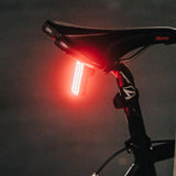 Bicycle tail light attached to a black seat on a dark background