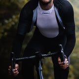 A person wearing a black long-sleeved undershirt and shorts, cycling outdoors.