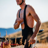 Man in cycling gear standing with a bicycle in a natural setting