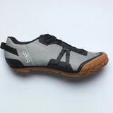 Gray and black cycling shoe with brown sole on a light gray background