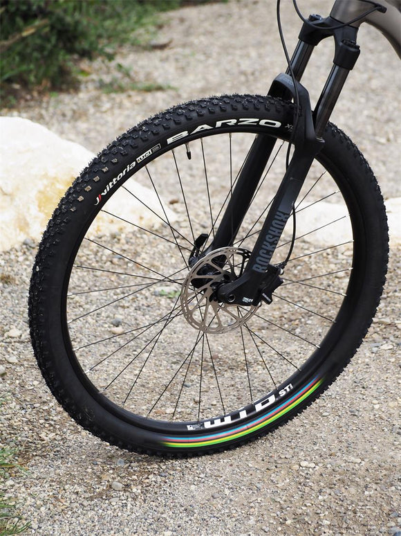 Close-up of a bicycle wheel with visible brand names on a gravel surface