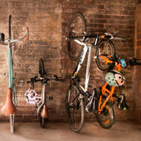 Bicycles hanging on a brick wall with helmets attached