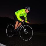 Cyclist in a bright yellow jacket riding a bicycle at night.