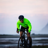 Cyclist in a bright green jacket riding on a road with a blurred background