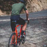 Cyclist on an orange bicycle on a mountain road