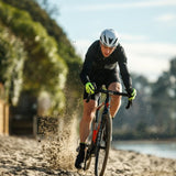 Cyclist riding on a dirt path with trees and water in the background