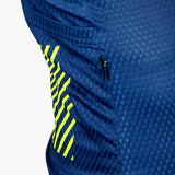 A close-up of a navy blue cycling jersey with yellow geometric patterns on the sleeves, featuring a zipper and pockets.