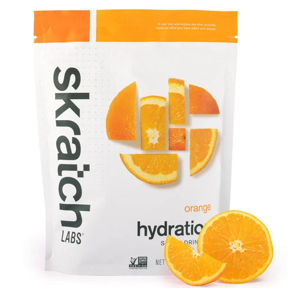 A package of Skratch Labs Sport Hydration drink mix with orange flavor, alongside sliced oranges.